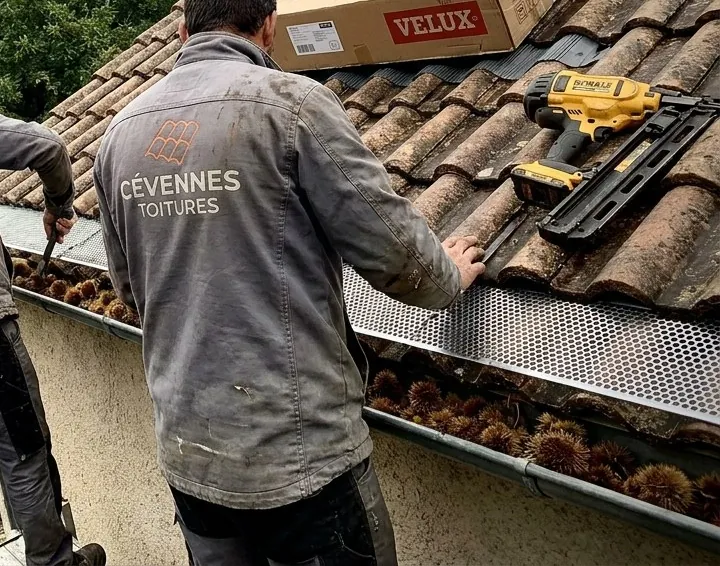Couvreur de Cévennes Toitures posant une grille sur une gouttière remplie de bogues de châtaignes à Alès